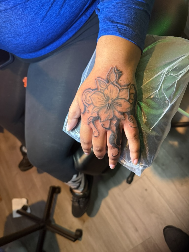 Black and gray floral hand tattoo with ornamental linework