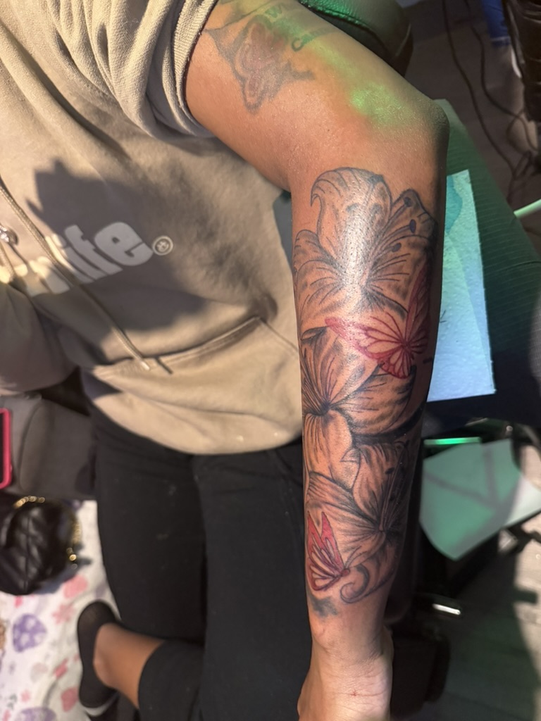 Neo traditional forearm tattoo with black and grey flowers and red-pink butterflies